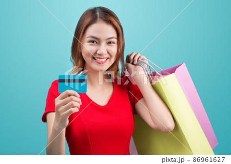 Santa asian woman holding shopping bags and credit card against blue vignette Santa asian woman holding shopping bags and credit card against blue vignette 86961627