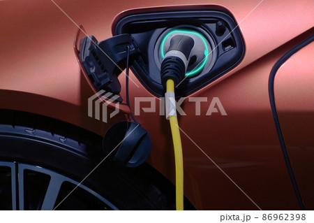 Close-up hand grip plug of industrial electric charging machine connected with socket charge on white electric car for rechargeable battery, zero emission vehicle and green energy for smart life 86962398