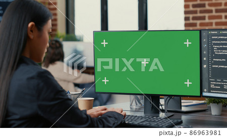 Focus on computer screen with green screen chroma key mockup in front of asian programer writing code 86963981