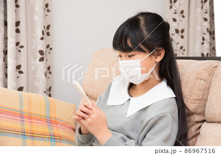 風邪を引いて体温を計る小学生の女の子 風邪を引いて体温を計る小学生の女の子 86967516