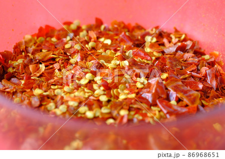 close up of red chili flakes in a bowl on red  86968651