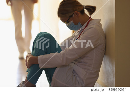 A female doctor is sitting on the floor in the hallway, close-up A female doctor is sitting on the floor in the hallway, close-up 86969264