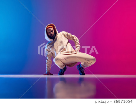 Studio shot of young flexible sportive man dancing breakdance in white outfit on gradient pink blue background. Concept of action, art, beauty, sport, youth Studio shot of young flexible sportive man dancing breakdance in white outfit on gradient pink blue background. Concept of action, art, beauty, sport, youth 86971054