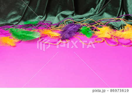 Festive carnival background, green velvet curtain colorful feather beads necklace for Mardi Gras  86973619