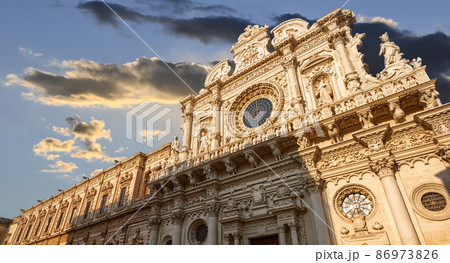 Lecce, Puglia, Italy. August 2021. The church of Santa Croce is the finest example of Lecce baroque. The view displays it in all its beauty with late afternoon light. People. 86973826