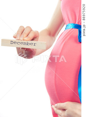 Woman in pregnant wearing pink dress with blue ribbon and showing word december Woman in pregnant wearing pink dress with blue ribbon and showing word december 86975920