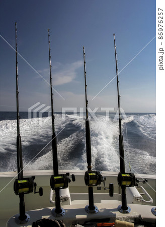 Fishing spinning rods for deep ocean fishing on the stern of high-speed yacht. Fishing spinning rods for deep ocean fishing on the stern of high-speed yacht. 86976257