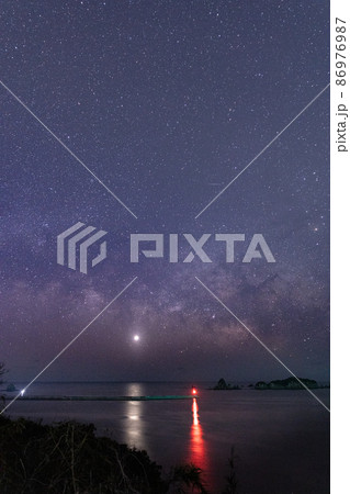 宮崎県日南市池ケ山から七つ岩と並ぶ小場島の上に広がる星空に横に流れる天の川と灯台と共に海を照らす金星 86976987