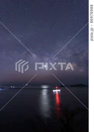 宮崎県日南市池ケ山から七つ岩と並ぶ小場島の上に広がる星空に横に流れる天の川と灯台と共に海を照らす金星 86976988