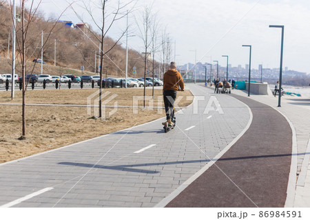 Man riding electrical scooter on embankment in spring time. Modern urban transport concept 86984591