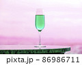 ピンク色の風景に溶け込む青緑のシャンペングラスと白い光とコピースペース 86986711
