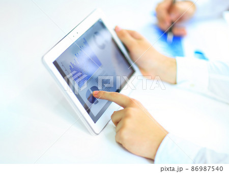 Modern people doing business, graphs and charts being demonstrated on the screen of a touch-pad Modern people doing business, graphs and charts being demonstrated on the screen of a touch-pad 86987540