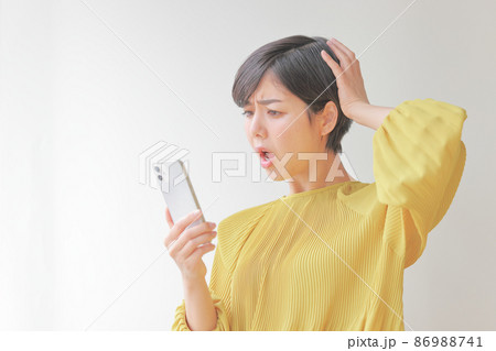 スマホを見て頭を抱える女性1 スマホを見て頭を抱える女性1 86988741