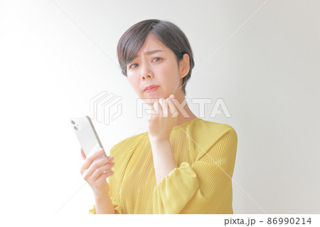 スマホを持ち握りこぶしで悲しい表情の女性1 スマホを持ち握りこぶしで悲しい表情の女性1 86990214