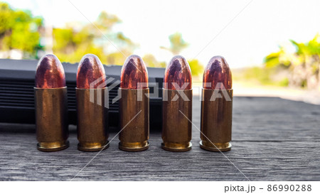 Black artificial hand gun and golden shiny bullets 86990288