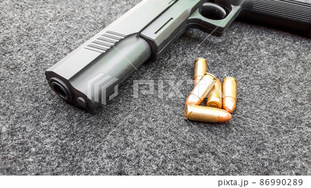 Black artificial hand gun and golden shiny bullets Black artificial hand gun and golden shiny bullets 86990289