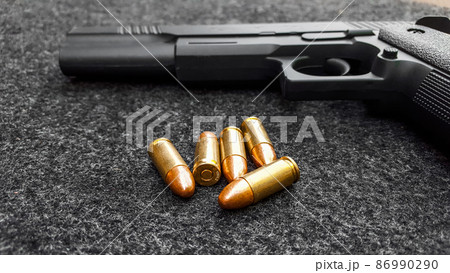 Black artificial hand gun and golden shiny bullets 86990290