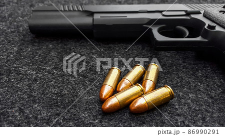 Black artificial hand gun and golden shiny bullets Black artificial hand gun and golden shiny bullets 86990291