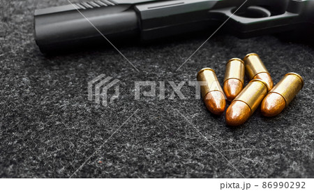 Black artificial hand gun and golden shiny bullets 86990292
