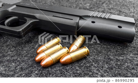 Black artificial hand gun and golden shiny bullets Black artificial hand gun and golden shiny bullets 86990295
