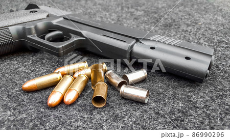Black artificial hand gun and golden shiny bullets Black artificial hand gun and golden shiny bullets 86990296