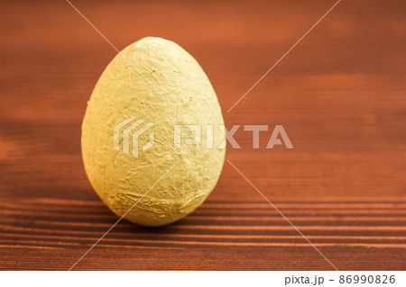 One decorative light yellow egg on a wooden background. 86990826