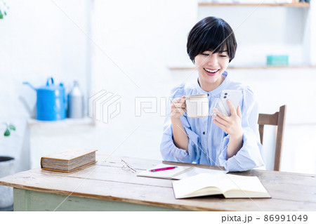 リビングで勉強中にコーヒとスマホで気分転換する若い女性 リビングで勉強中にコーヒとスマホで気分転換する若い女性 86991049