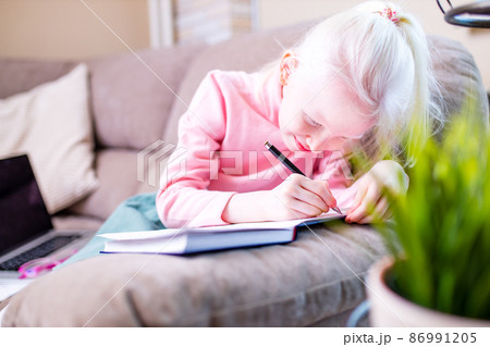beautiful little girl getting online distance lesson in living room beautiful little girl getting online distance lesson in living room 86991205