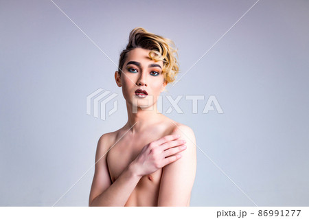 asian man with luxurious blonde hair and gorgeous make-up in white wall studio background passion look at camera 86991277