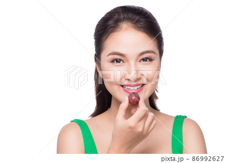 Young beautiful asian woman eating fresh grapes isolated on white background. Young beautiful asian woman eating fresh grapes isolated on white background. 86992627