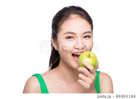 Attractive smiling young asian woman eating green apple isolated over white background. Attractive smiling young asian woman eating green apple isolated over white background. 86993199