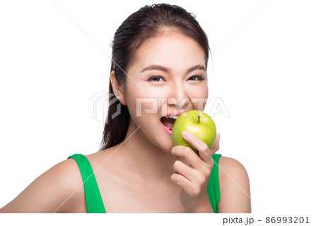 Young beautiful asian woman eating fresh green apple on white background Young beautiful asian woman eating fresh green apple on white background 86993201