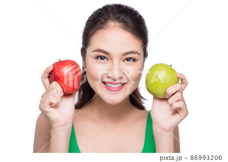 Attractive smiling young asian woman holding green apple isolated over white background. 86993206