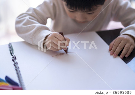 スケッチブックにクレヨンで絵を描く4歳の男の子 86995689