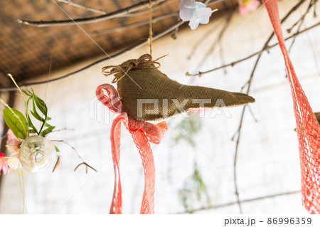 Hanging ribbon and bird shape linen fabric and flower clear glass vase on background , artificial flowers hang in a wedding party or interior. Decoration indoors 86996359