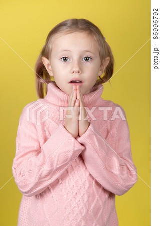 Begging little caucasian elementary age school girl looking at the camera Begging little caucasian elementary age school girl looking at the camera 86996792