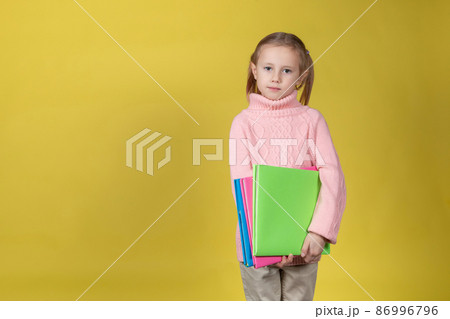 Portrait of attractive elementary age school girl on yellow background 86996796