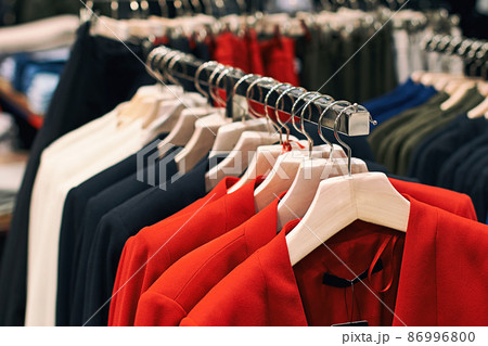 Woman jackets in red, blue, white and other colors on hangers in a retail clothes store. Woman jackets in red, blue, white and other colors on hangers in a retail clothes store. 86996800