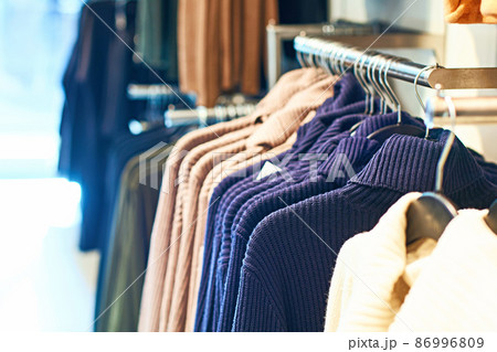 Woman pullover sweaters in different colors on hangers in a retail clothes store. 86996809