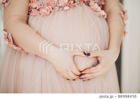 Close up of pregnant woman in powder long dress Close up of pregnant woman in powder long dress 86998456