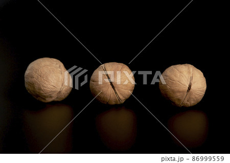 Three walnuts at a distance from each other on a black background Three walnuts at a distance from each other on a black background 86999559