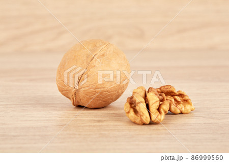 The walnut is whole, and next to it lies a peeled walnut. The walnut is whole, and next to it lies a peeled walnut. 86999560