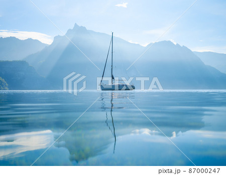 A yacht against the backdrop of the mountains in Switzerland. Calm water and bright sunny day. A yacht against the backdrop of the mountains in Switzerland. Calm water and bright sunny day. 87000247