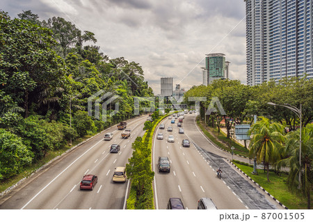 Highway with cars surrounded by greenery and skyscrapers Highway with cars surrounded by greenery and skyscrapers 87001505