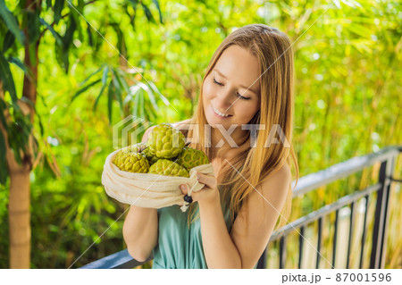 Cherimoya in a reusable bag in female hands. Zero waste concept, plastic free concept. Healthy clean eating diet and detox. Summer fruits 87001596