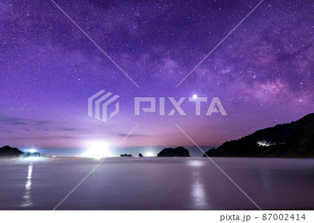 宮崎県日南市贄波浜から黒島と並ぶ烏帽子島の上に広がる星空に横に流れる天の川と灯台と共に海を照らす金星 87002414
