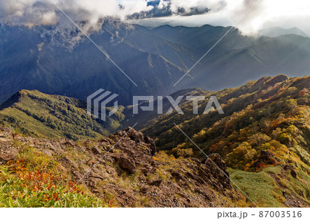 紅葉の谷川岳・西黒尾根の登りから見る朝日差さす山並み 87003516