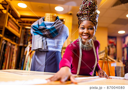 tanzanian woman with snake print turban over hear working in fabrics shop 87004080