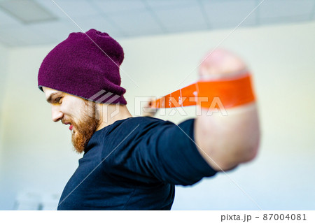man with amputee hand training with elastic band in gym 87004081