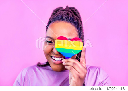 afro american woman holding a heart shape in pink studio background 87004118